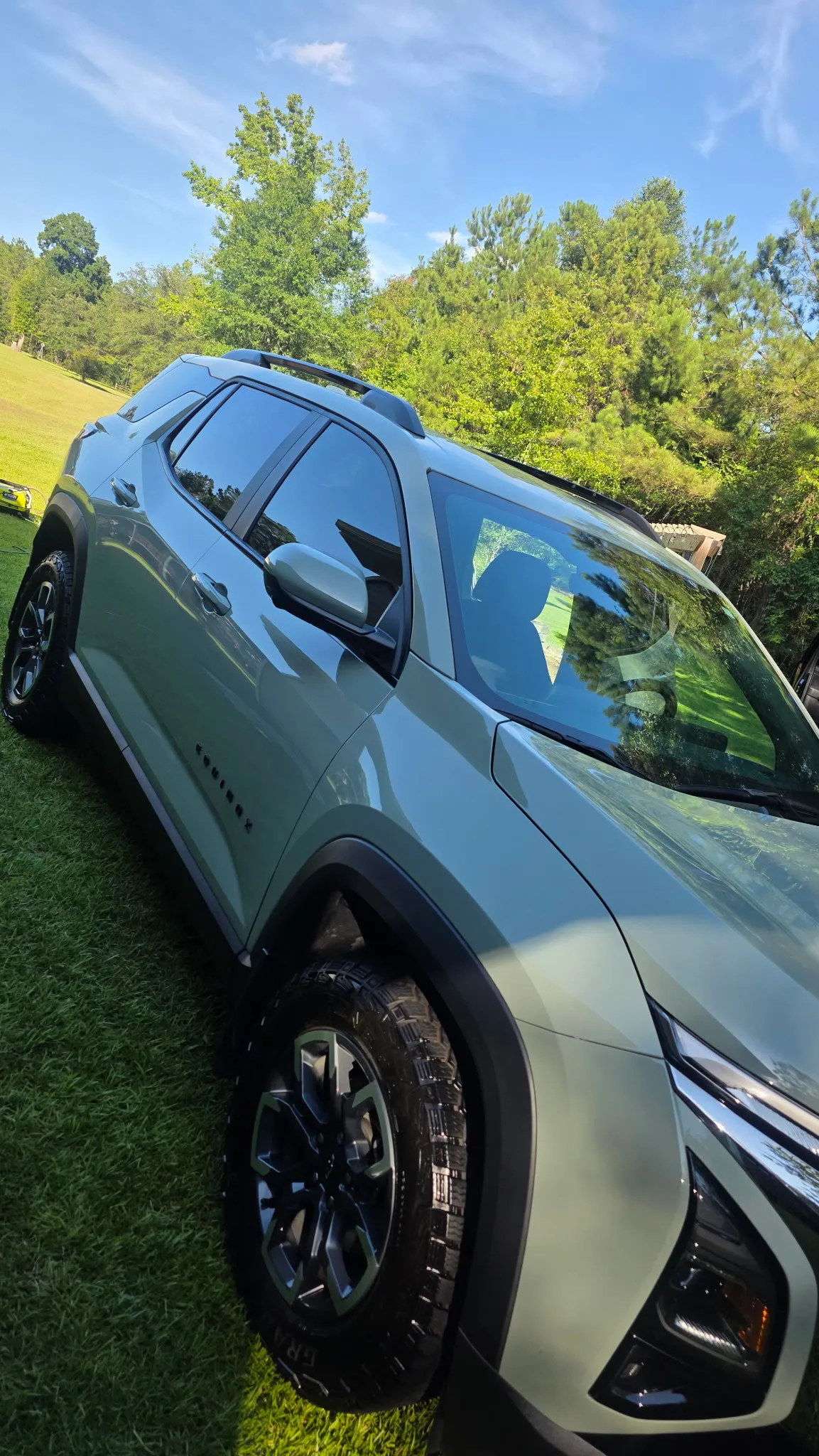 Teal Honda crossover parked on grass, paint clean and reflecting the sky