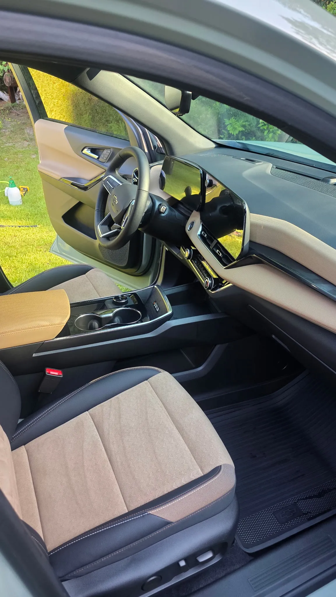 Front interior of a sedan with clean tan cloth seats and dark dashboard